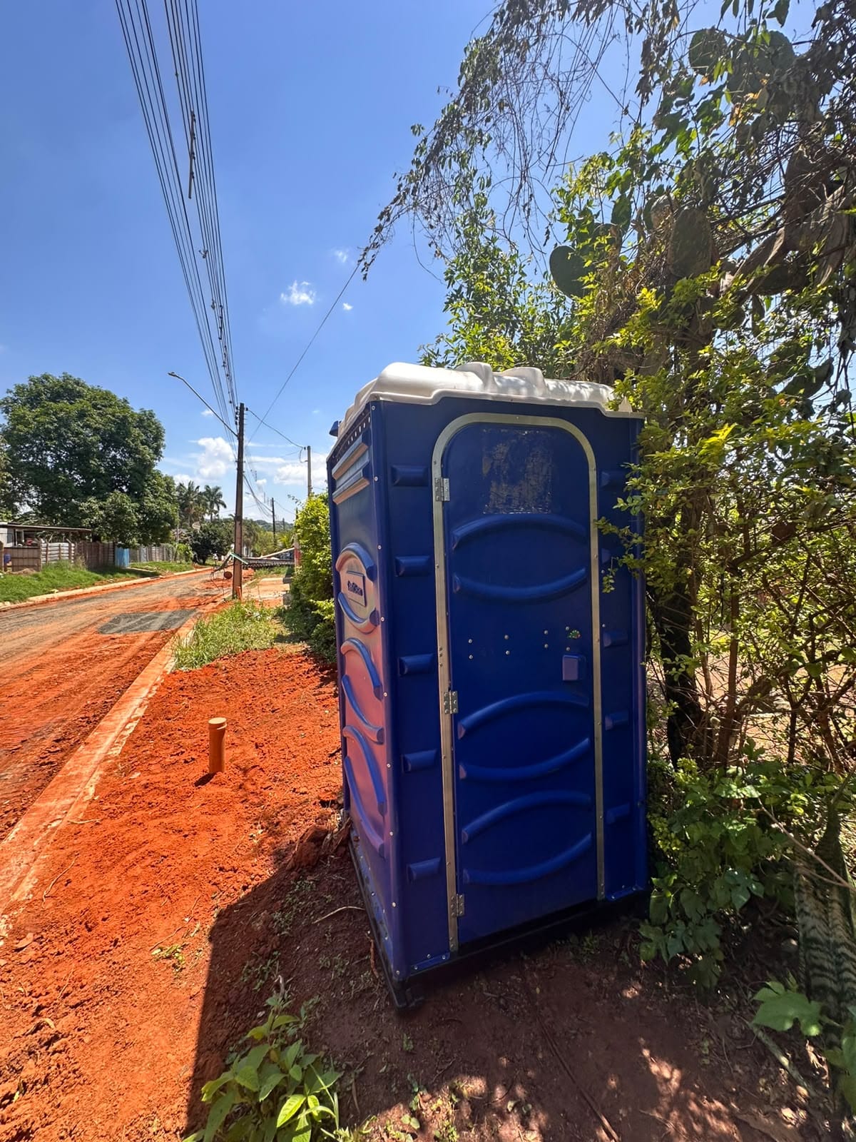 Banheiro químico azul posicionado ao lado de uma obra de rua