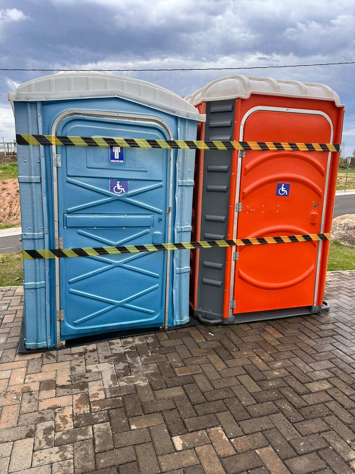 Dois banheiros PCD/PNE, um azul-claro e um laranja, com o símbolo de acessibilidade na porta