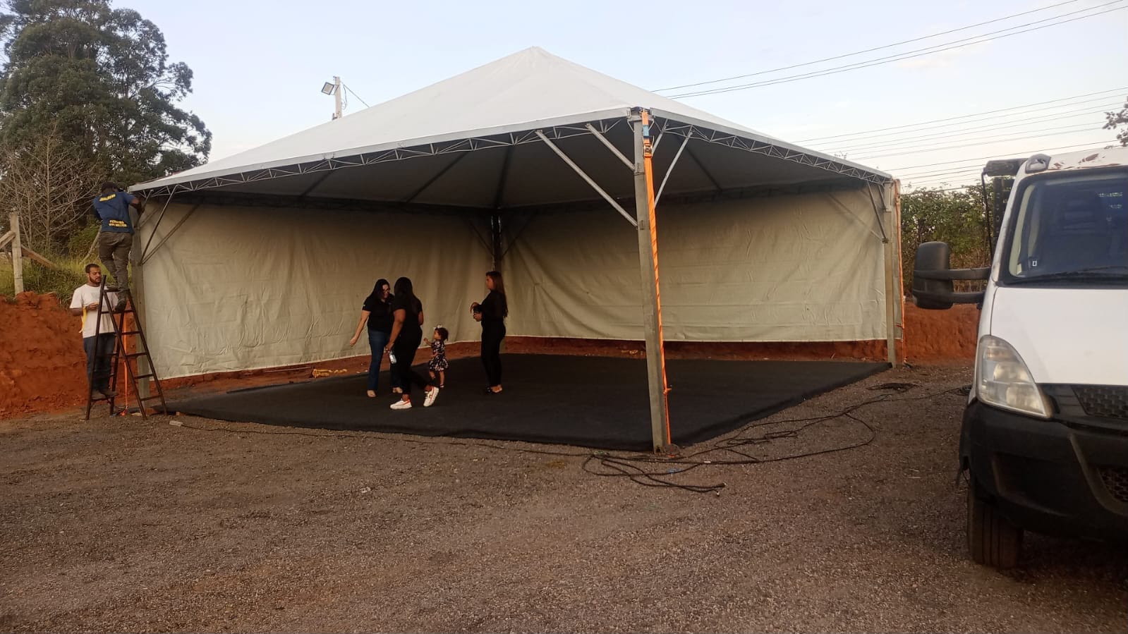 Tenda branca com as laterais fechadas, com pessoas na parte interna