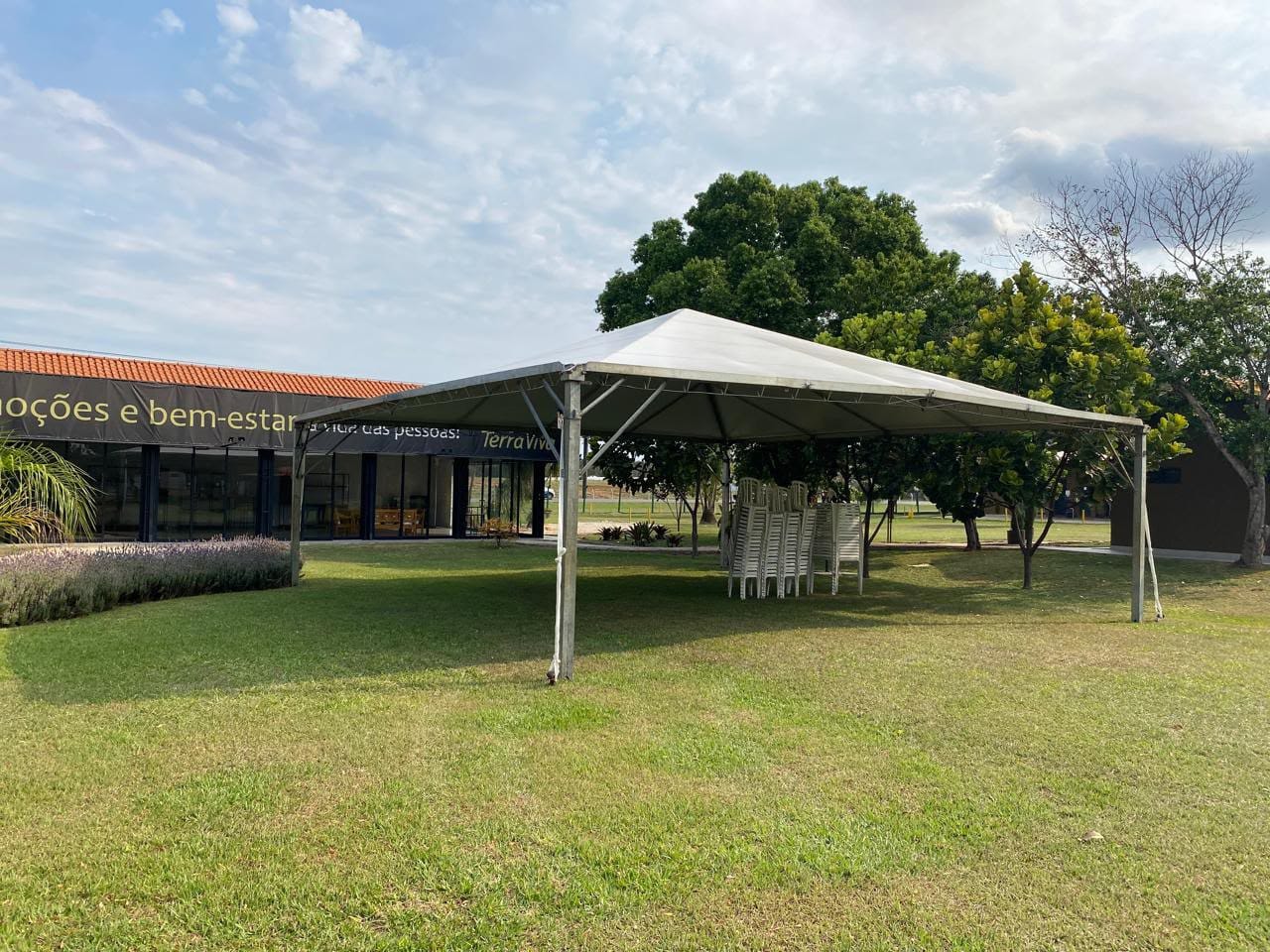 Tenda branca montada no gramado, ao lado do prédio de um espaço de eventos