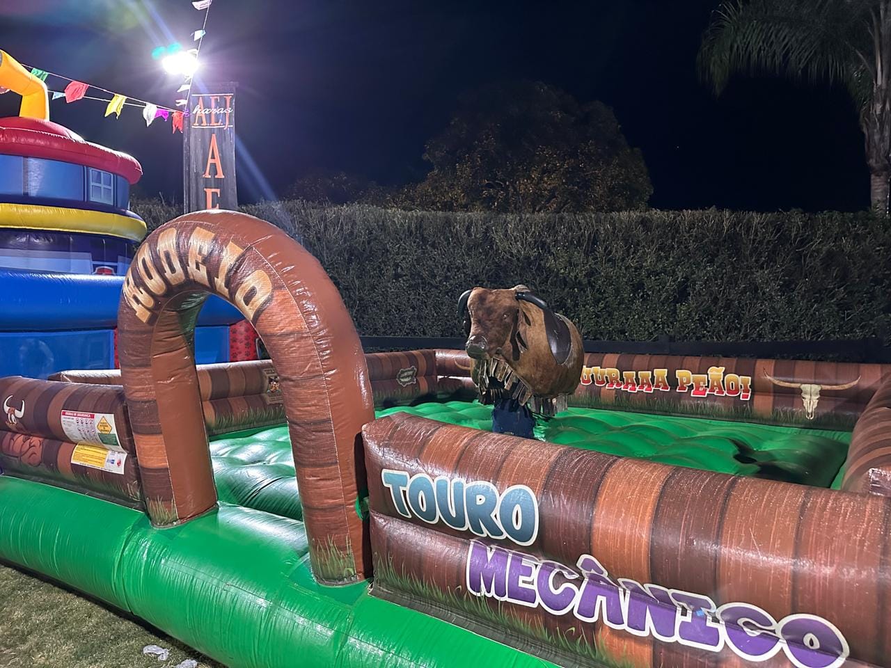 Touro mecânico montado à noite em festa, com a arena inflável iluminada