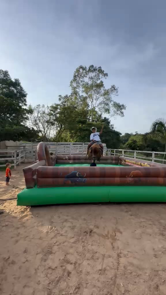 Touro mecânico em funcionamento, visto de longe, com a arena inflável