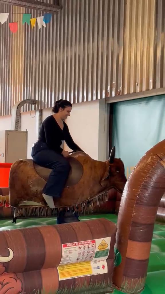 Participante montada no touro mecânico em funcionamento, dentro da arena inflável