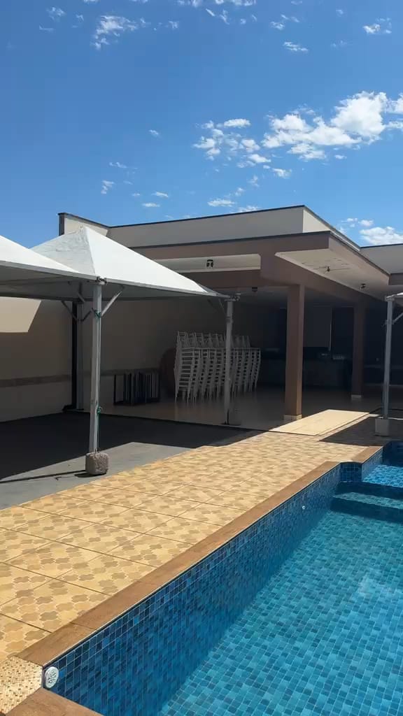 Tendas brancas montadas em um espaço com piscina, em dia de céu azul